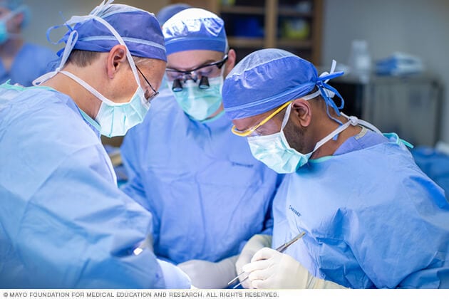 Médicos especialistas en salud masculina hacen un procedimiento, vestidos en ropa quirúrgica.