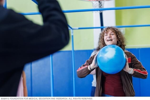 A young woman laughs as she throws a large exercise ball in a session.