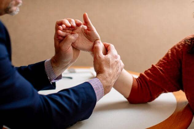 A specialist in hand rehabilitation performs a hand and wrist exam on a patient.