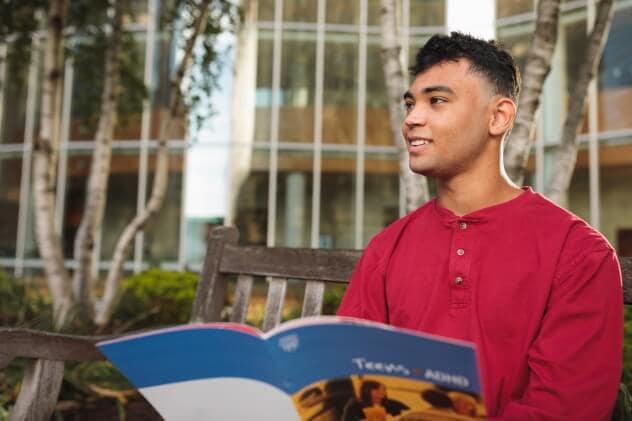 A young person sits on a bench on the Mayo Clinic campus.