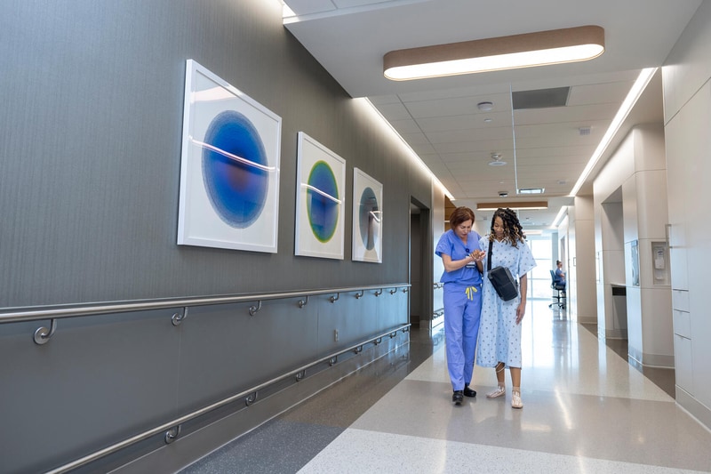 A Mayo Clinic nurse assists a patient walking through a hospital hallway.