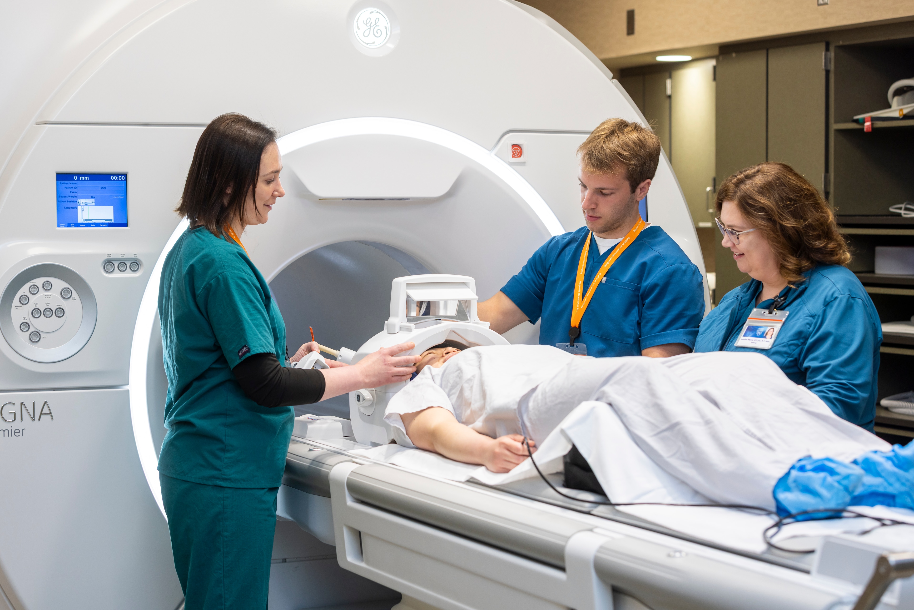 Technicians prepare a person for an MRI scan.