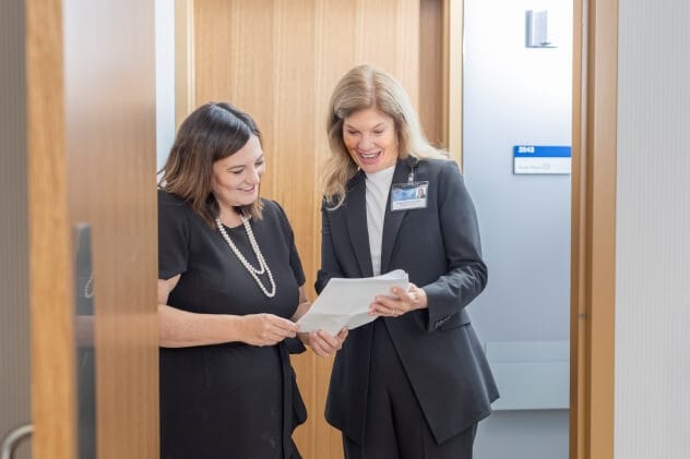 A Bariatric Center physician and another person review some information outside an office.
