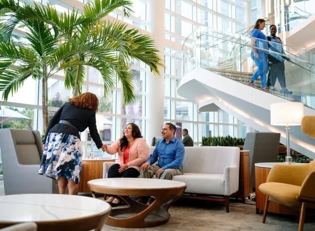 Bariatric Center visitors waiting on a sofa are greeted by a Mayo Clinic staff person.