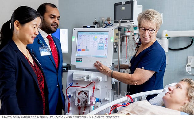 Mayo Clinic kidney specialists and a nurse monitor the care of a person receiving dialysis in a clinical setting.