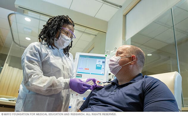 A nurse attaches a hemodialysis catheter to a patient in a dialysis unit.