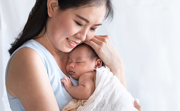 A smiling mother holding her newborn to her chest.