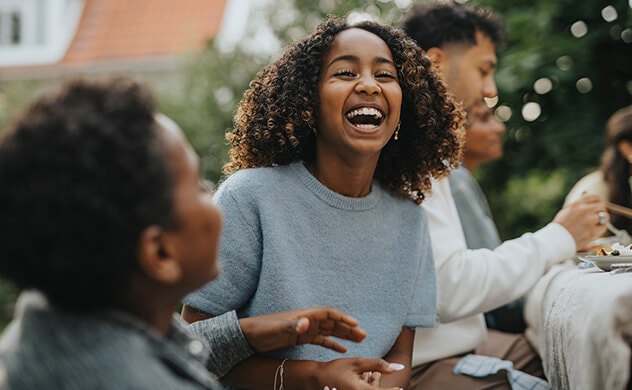 A girl laughs during an outdoor dinner party.