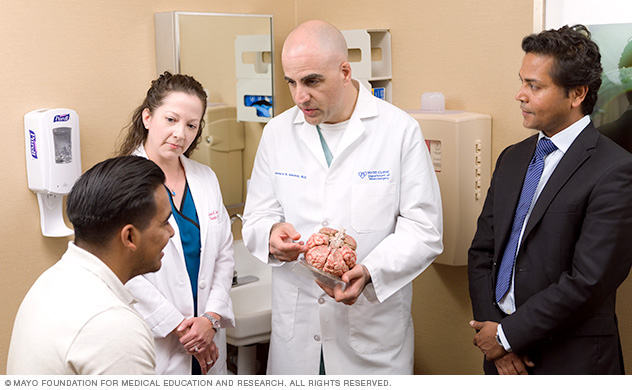 أطباء وجراحو الأعصاب في Mayo Clinic (مايو كلينك) يتحدثون مع مريض.
