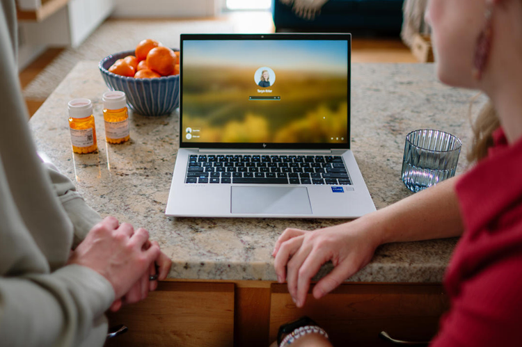 Patient and caregiver using laptop at home.
