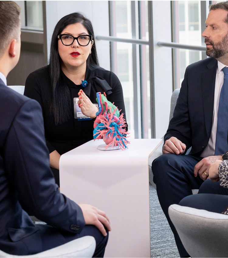 Four colleagues reviewing anatomical model