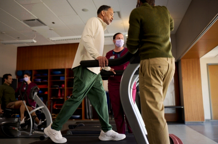 Person on treadmill helped by staff in a physical rehab setting